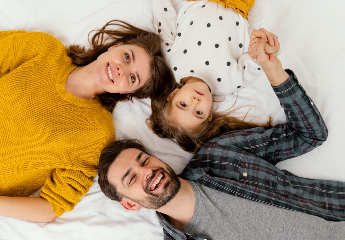 Educar con ejemplo. Una pareja tumbada en la cama con su hija.